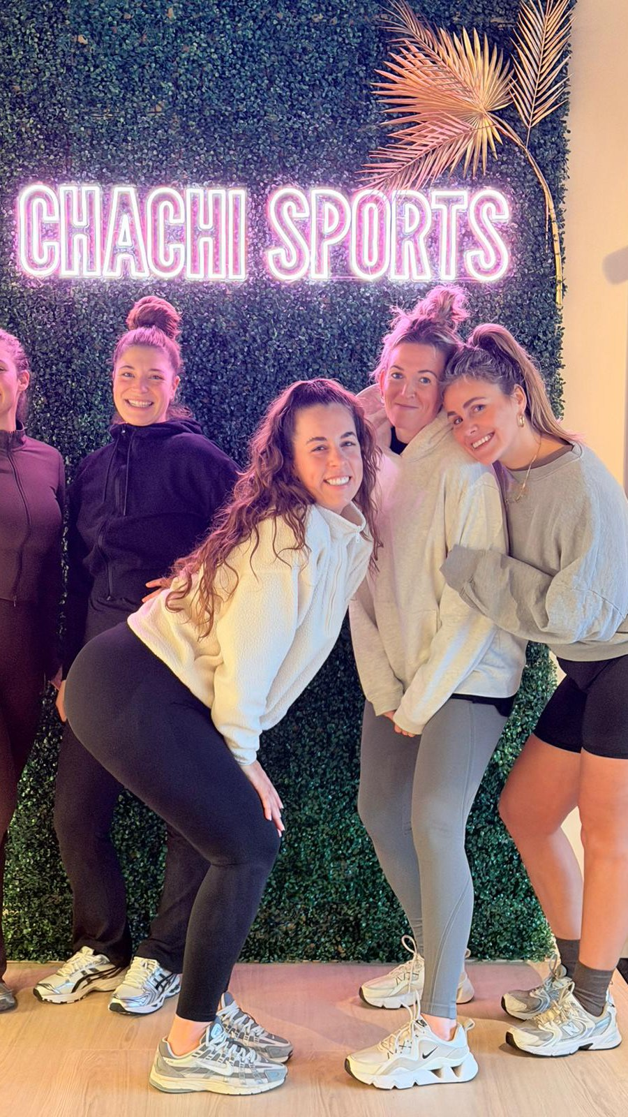 Groep vrouwen samen bij de neon Chachi Sports sign in een gezellige studio